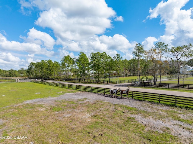 view of property's community with a yard, a rural view, and fence