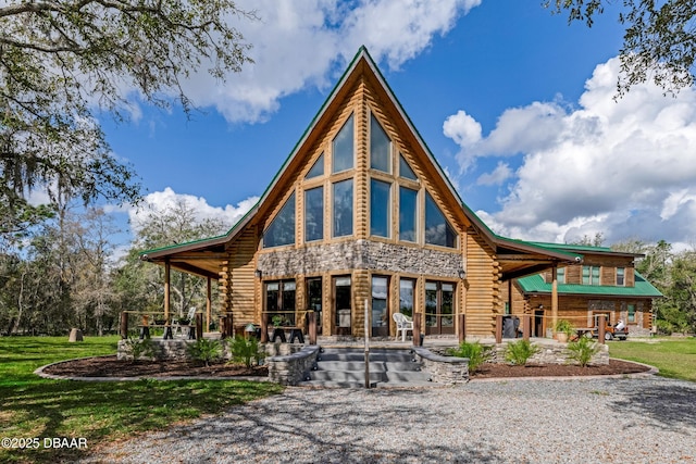 rear view of house featuring log exterior and a yard