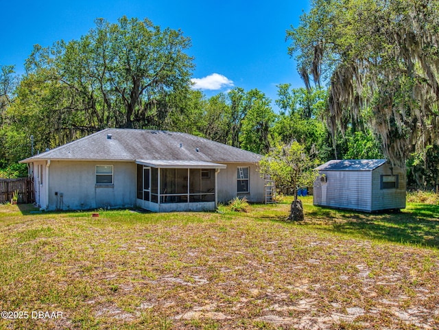 back of property with a sunroom, an outdoor structure, a lawn, and a storage unit