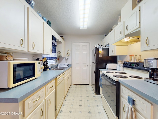 kitchen with light floors, a textured ceiling, under cabinet range hood, white appliances, and a sink