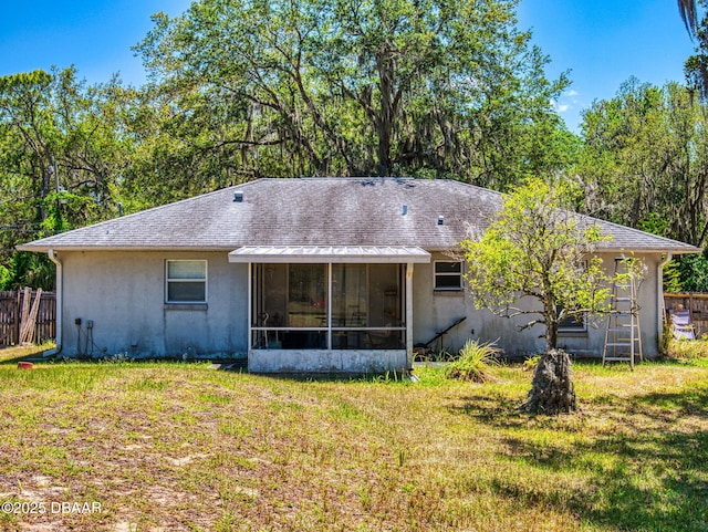 rear view of property with a sunroom, stucco siding, fence, and a lawn