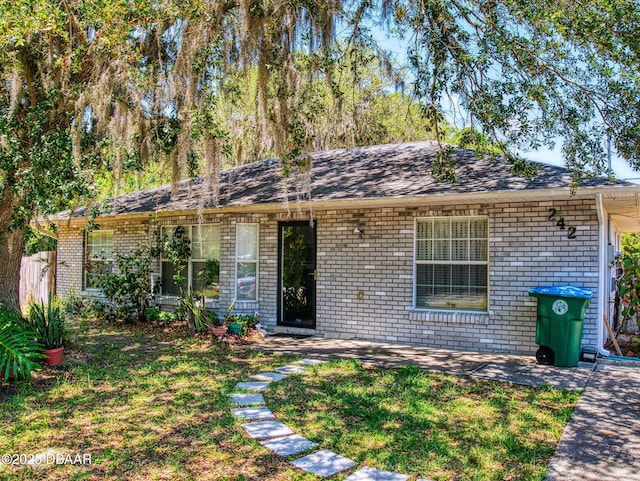 ranch-style house with a front yard, a patio, and brick siding