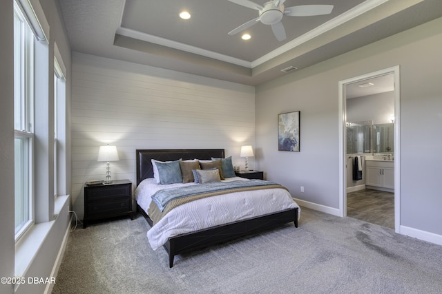 bedroom featuring crown molding, ensuite bathroom, a tray ceiling, and carpet