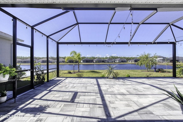 view of patio featuring glass enclosure and a water view