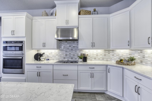 kitchen featuring white cabinetry, stainless steel double oven, tasteful backsplash, and black cooktop