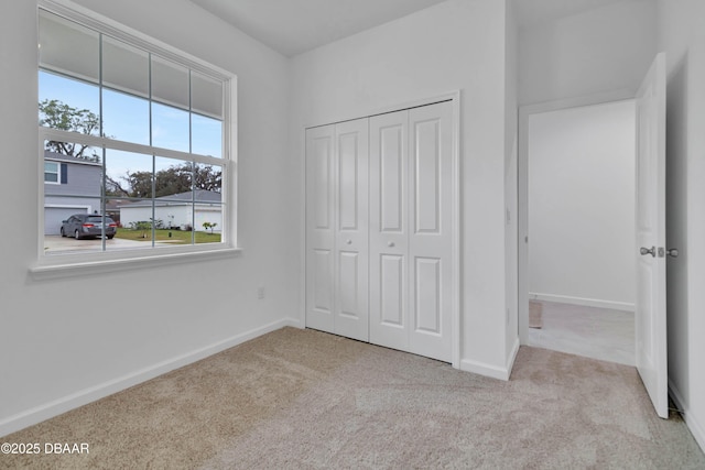 unfurnished bedroom with a closet, carpet flooring, and baseboards