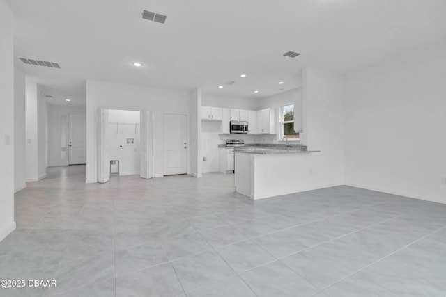 kitchen with stainless steel appliances, a peninsula, visible vents, and white cabinets