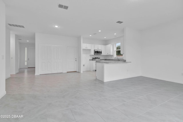 kitchen with a peninsula, appliances with stainless steel finishes, visible vents, and white cabinets