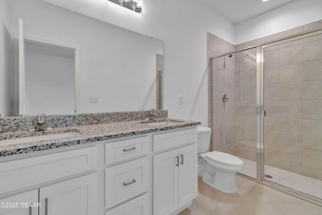 full bathroom featuring double vanity, a stall shower, a sink, and toilet