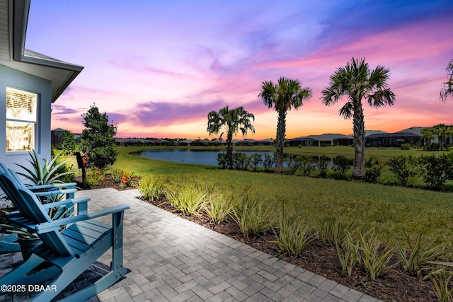 patio terrace at dusk with a lawn and a water view