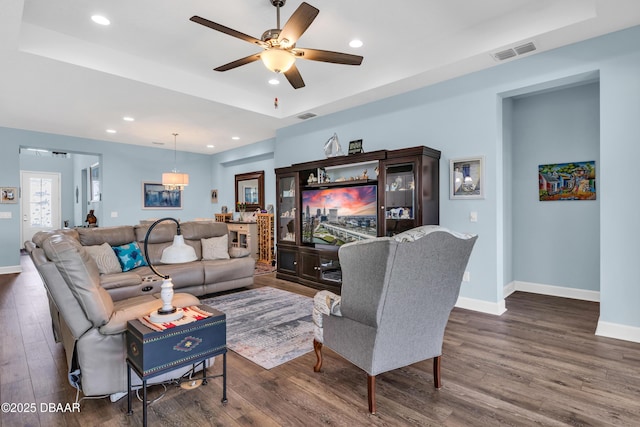 living room featuring ceiling fan, dark hardwood / wood-style flooring, and a raised ceiling