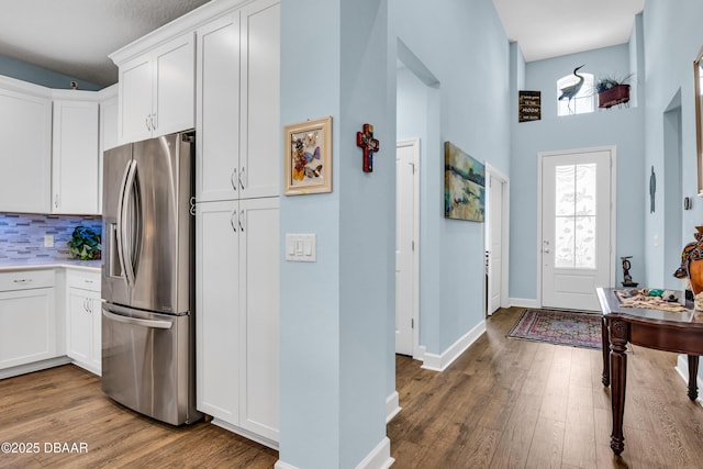 kitchen featuring white cabinetry, backsplash, stainless steel fridge, and wood-type flooring