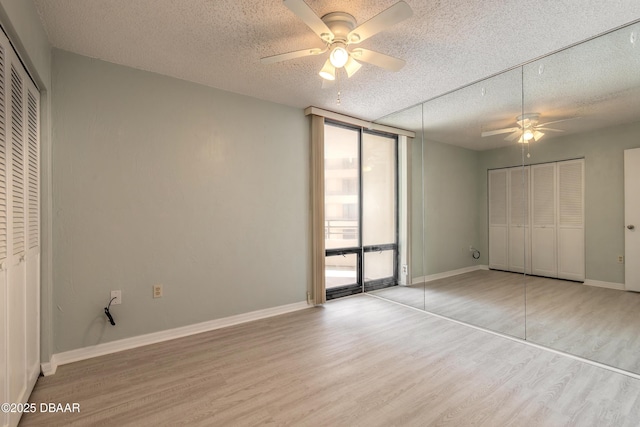 unfurnished bedroom featuring floor to ceiling windows, a textured ceiling, and wood finished floors
