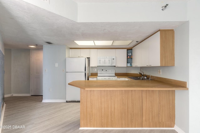 kitchen with visible vents, a sink, baseboards, a peninsula, and white appliances