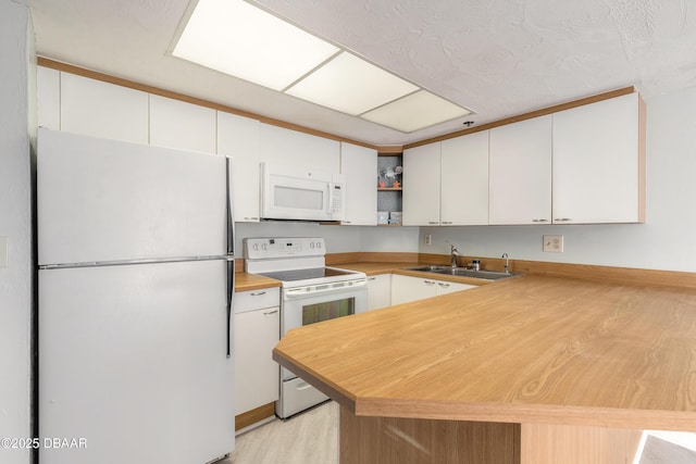 kitchen with light wood-type flooring, a sink, white cabinets, a peninsula, and white appliances