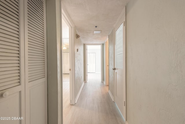 corridor featuring baseboards and light wood-style floors
