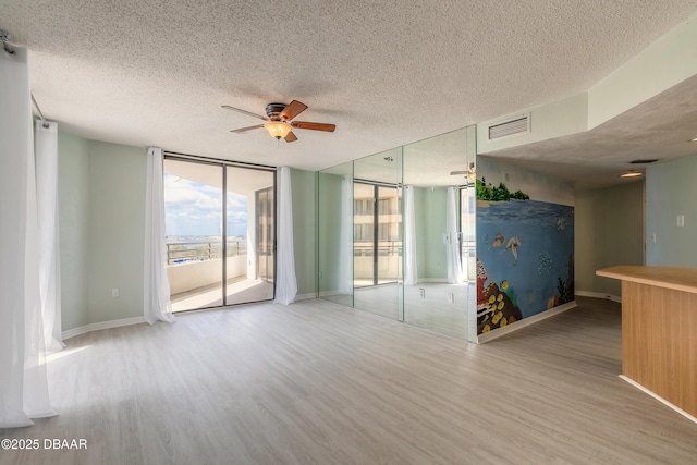 spare room featuring visible vents, wood finished floors, baseboards, a textured ceiling, and a ceiling fan