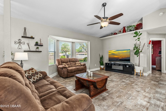 living room with ceiling fan, baseboards, and vaulted ceiling