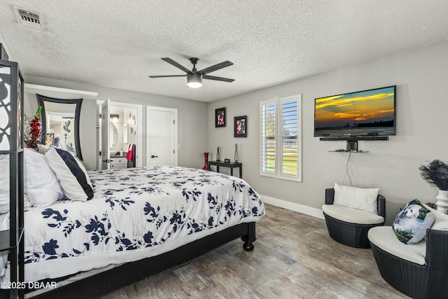 bedroom featuring visible vents, a ceiling fan, a textured ceiling, wood finished floors, and baseboards