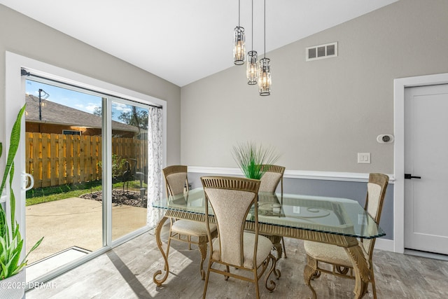 dining room featuring vaulted ceiling, wood finished floors, visible vents, and baseboards