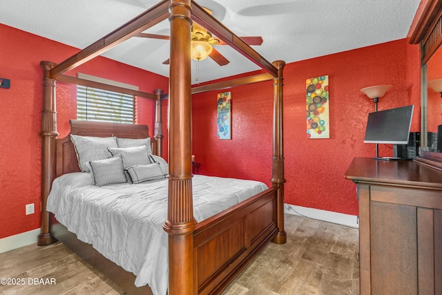 bedroom with a textured wall, a textured ceiling, baseboards, and wood finished floors