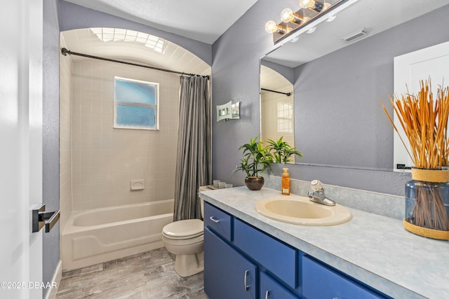 bathroom with visible vents, toilet, wood finished floors, shower / bath combination with curtain, and vanity