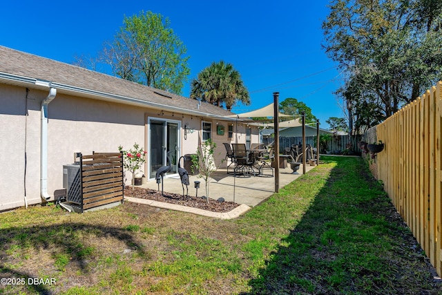 rear view of house with roof with shingles, stucco siding, a lawn, a patio area, and a fenced backyard