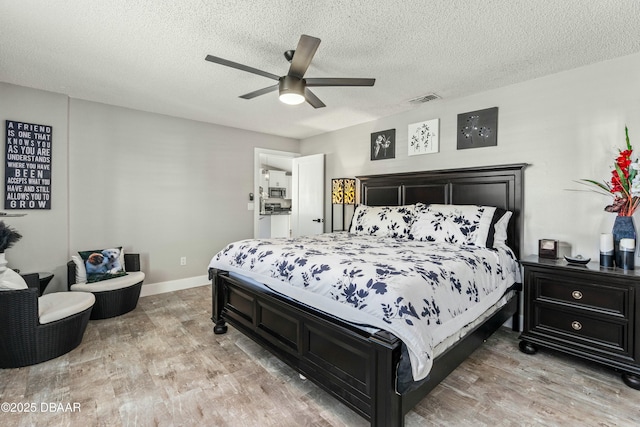 bedroom with light wood-type flooring, visible vents, and a textured ceiling