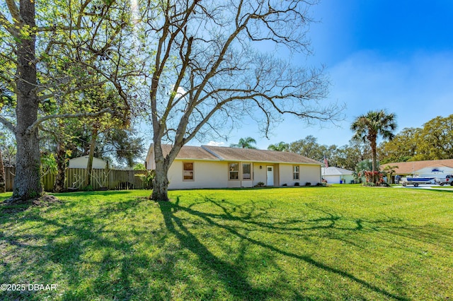 ranch-style house with fence, a front lawn, and stucco siding