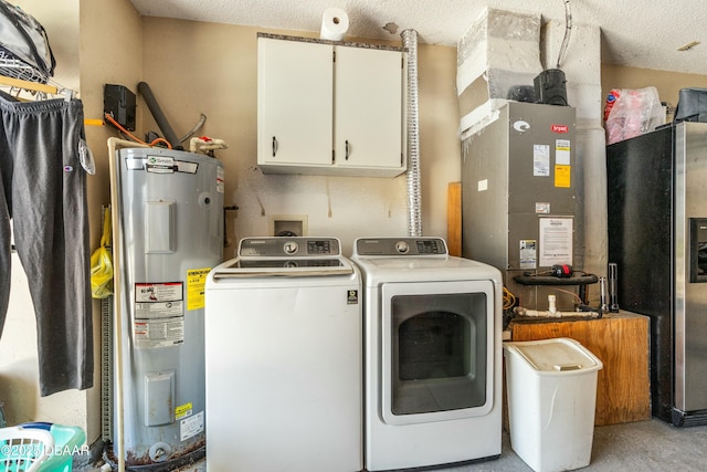 laundry room featuring heating unit, water heater, cabinet space, a textured ceiling, and washer and dryer