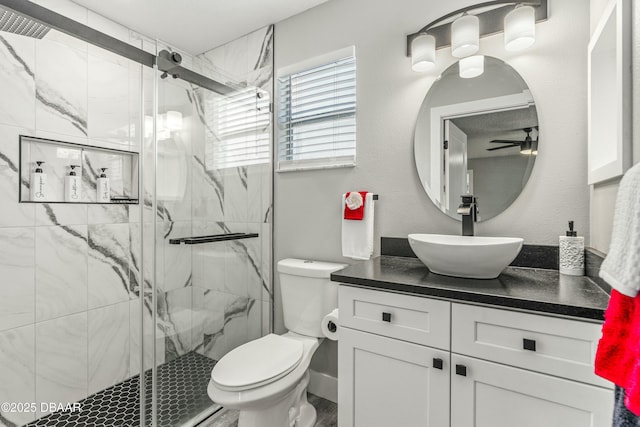 bathroom featuring ceiling fan, a marble finish shower, vanity, and toilet