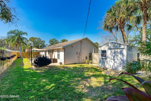 back of house with a storage shed, a yard, an outbuilding, and a fenced backyard