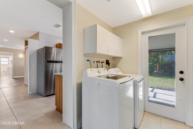 washroom featuring independent washer and dryer, light tile patterned floors, and cabinets