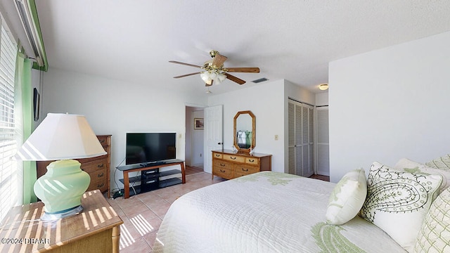 bedroom with a closet, light tile patterned floors, and ceiling fan