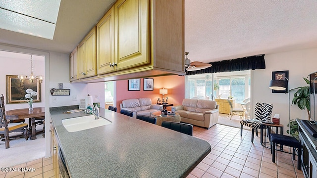 kitchen featuring light tile patterned floors, a chandelier, a textured ceiling, and sink