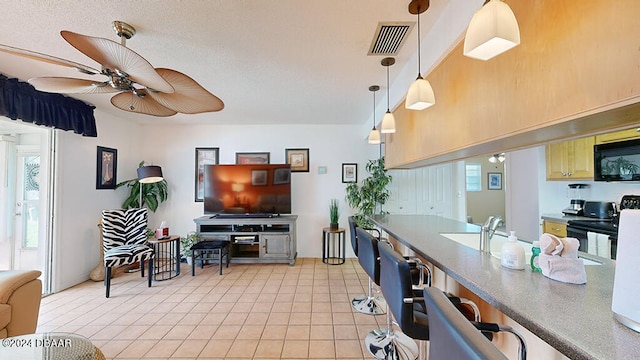 kitchen with hanging light fixtures, light tile patterned flooring, ceiling fan, and sink