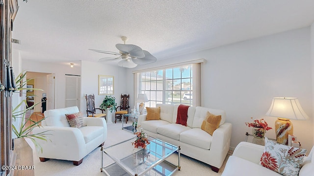 living room featuring a textured ceiling, light carpet, and ceiling fan