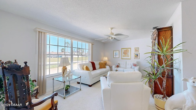 carpeted living room featuring ceiling fan and a textured ceiling