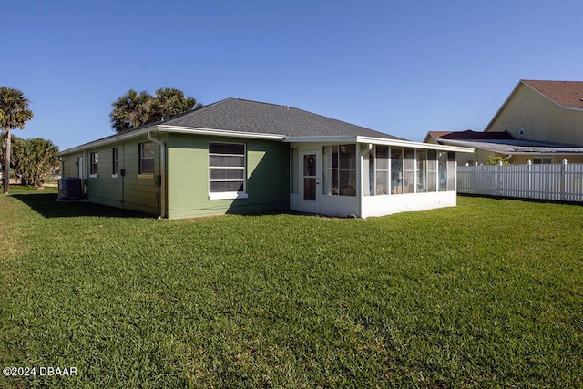 rear view of house with a lawn, a sunroom, and central AC