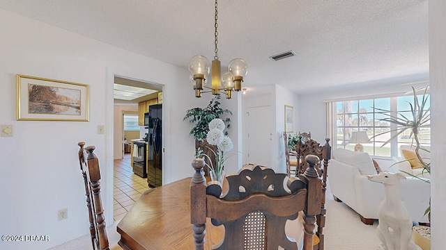 tiled dining space featuring a chandelier and a textured ceiling