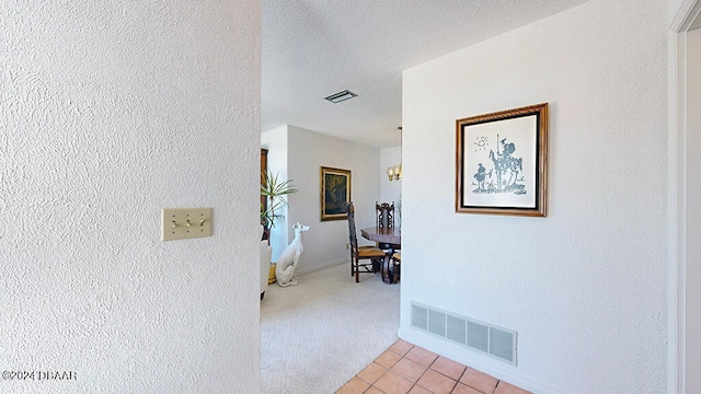 corridor with light colored carpet and a textured ceiling