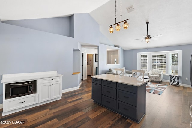 kitchen featuring white cabinetry, ceiling fan, dark hardwood / wood-style flooring, pendant lighting, and a center island