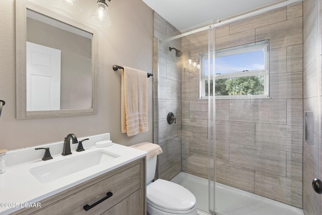 bathroom featuring toilet, vanity, and a shower with door