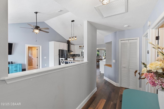 hall with vaulted ceiling, dark hardwood / wood-style floors, and a notable chandelier