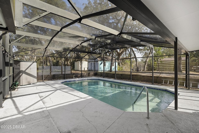 view of swimming pool featuring glass enclosure, a storage unit, and a patio