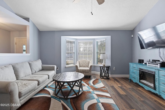 living room featuring ceiling fan, a textured ceiling, and dark hardwood / wood-style floors