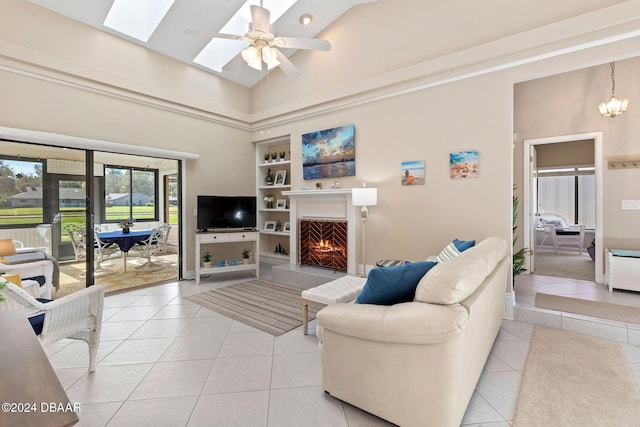 living room with built in features, light tile patterned floors, ceiling fan, and a warm lit fireplace
