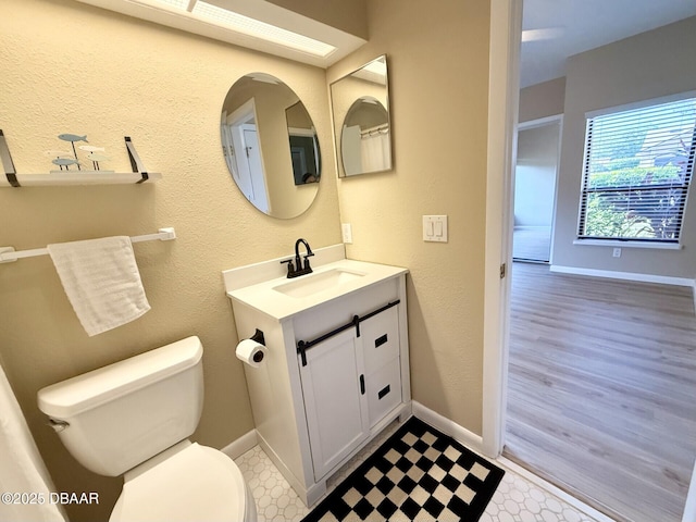 bathroom featuring toilet, vanity, and baseboards
