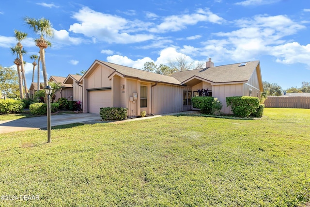 ranch-style house with a front yard, an attached garage, a chimney, fence, and concrete driveway
