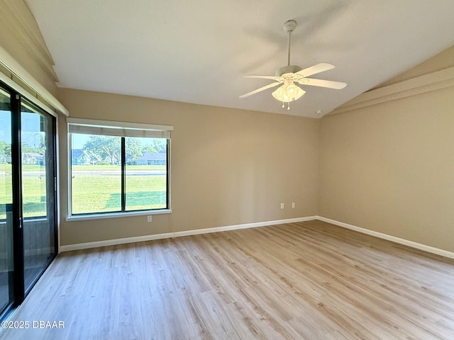 spare room featuring ceiling fan, light wood-type flooring, vaulted ceiling, and baseboards
